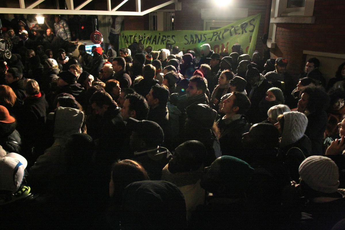 Beaucoup de monde dans la cour du bâtiment occupé. Une banderole intérimaires sans-papiers