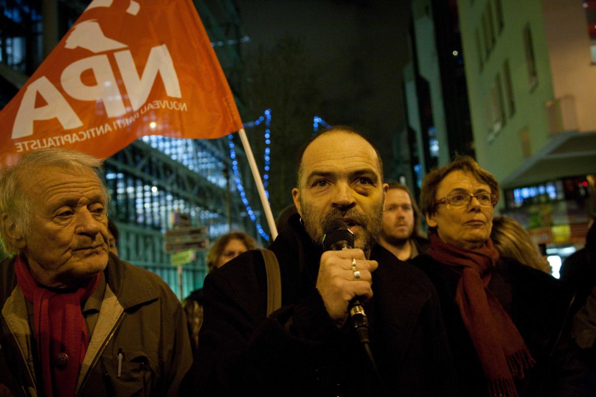 Denis Godard prenant la parole devant un drapeau NPA et Martine Billard, du Parti de Gauche.
