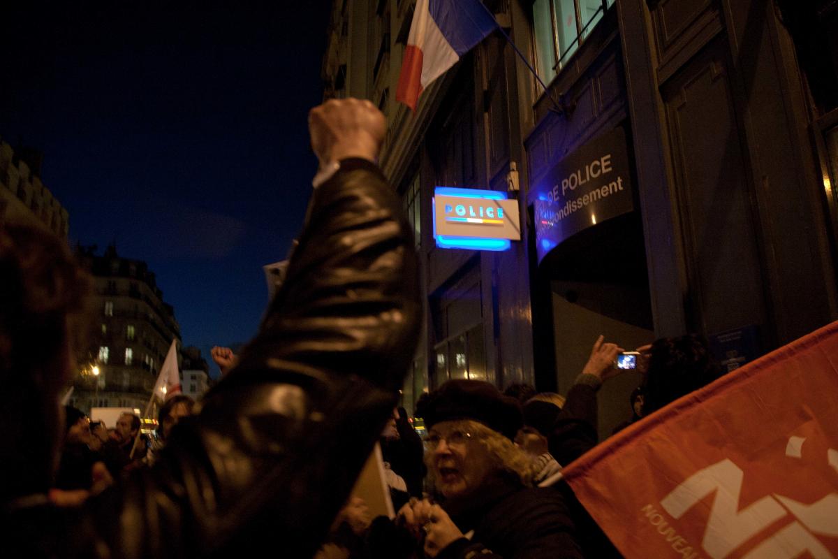 Poing levé et drapeau du NPA devant le commissariat.