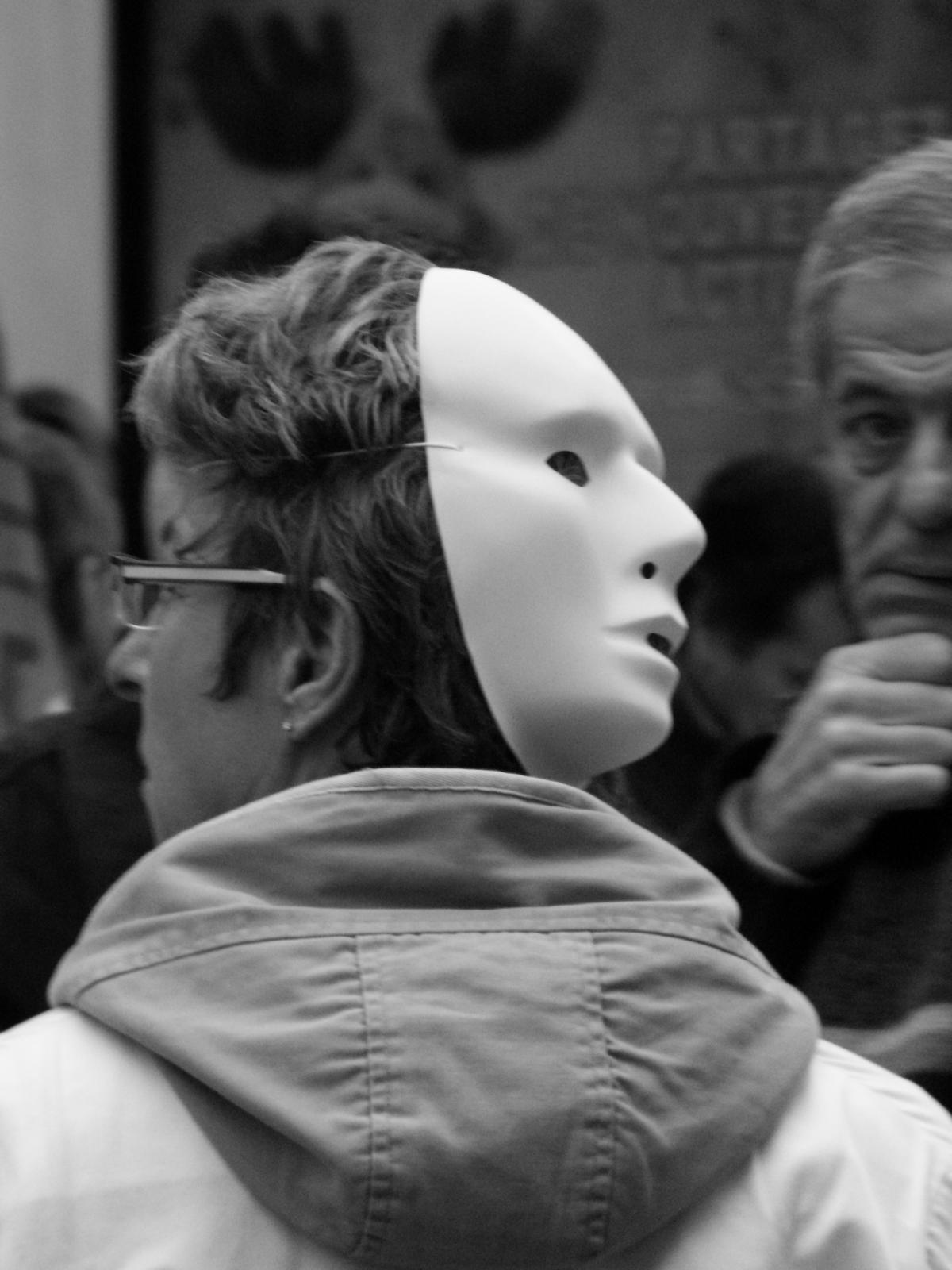 manifestant avec un masque blanc derrière la tête