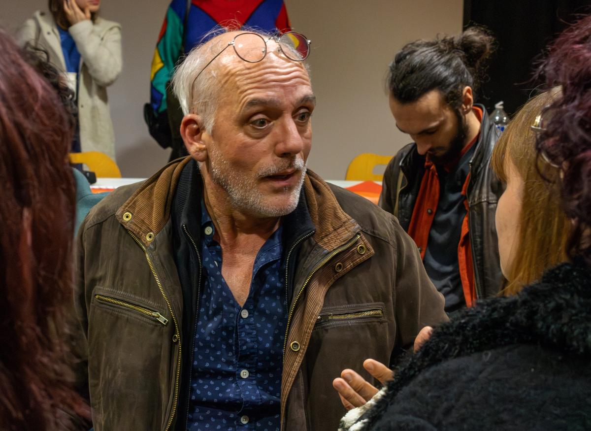 Photo de Philippe Poutou parlant avec les personnes venues à la réunion publique.