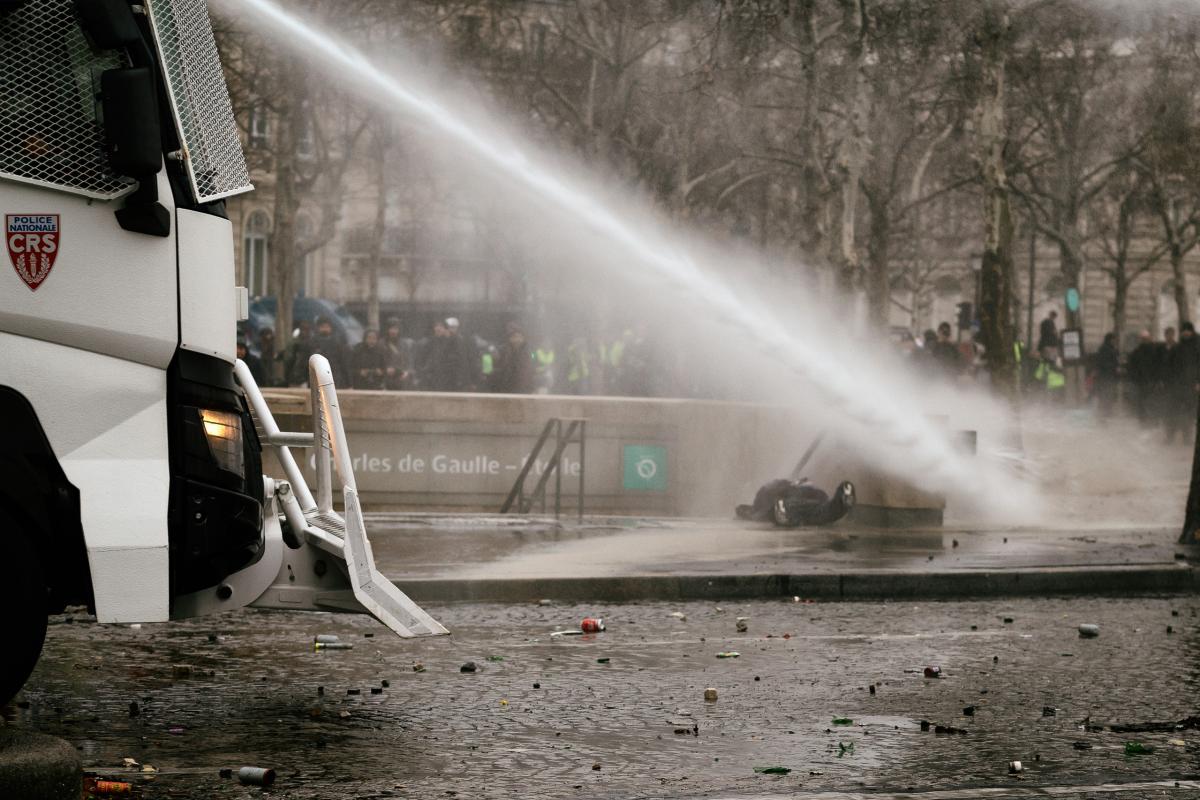 Un manifestant est jetté au sol avec le canon à eau. Il a failli tomber par les escaliers