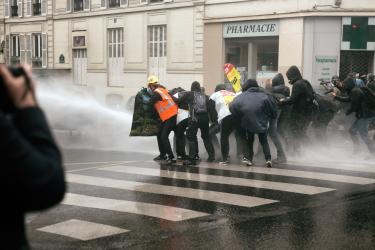Des manifestants se protègent du canon à eau derrière une banderole