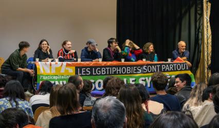 Photo de la tribune composée de 8 personnes prise depuis l'arriere du public qui se trouve au premier plan.