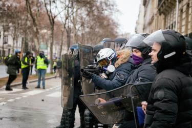 Un membre de la bac pointe les manifestants avec un lbd
