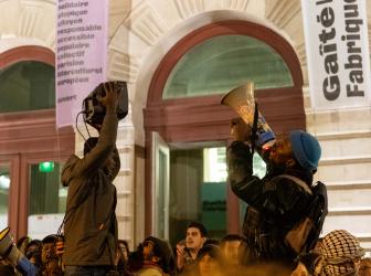 Porter par la foule, un homme au mégaphone et un autre qui tiens l'enceinte 