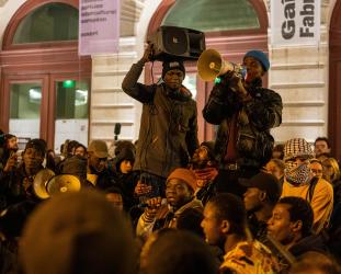 Un homme au micro et deux hommes portés par la foule