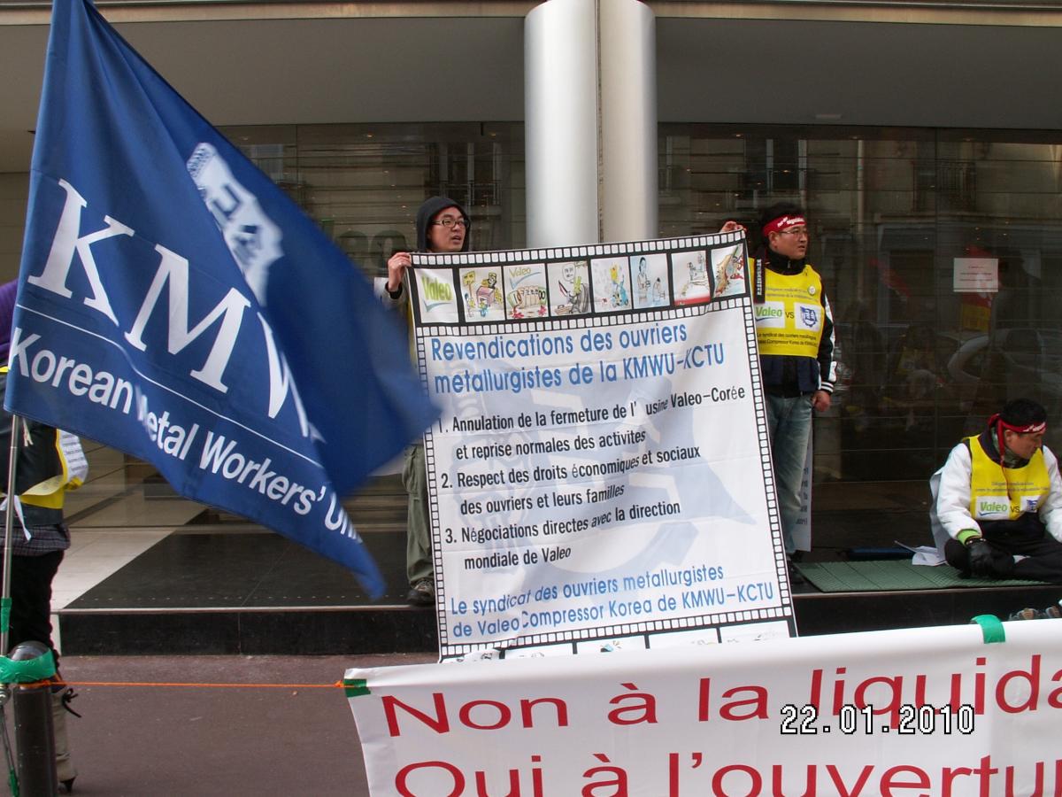 Délégation d'ouvriers coréens de Valeo devant le siège de Valeo à Paris avec le drapeau de leur syndicat KMWU