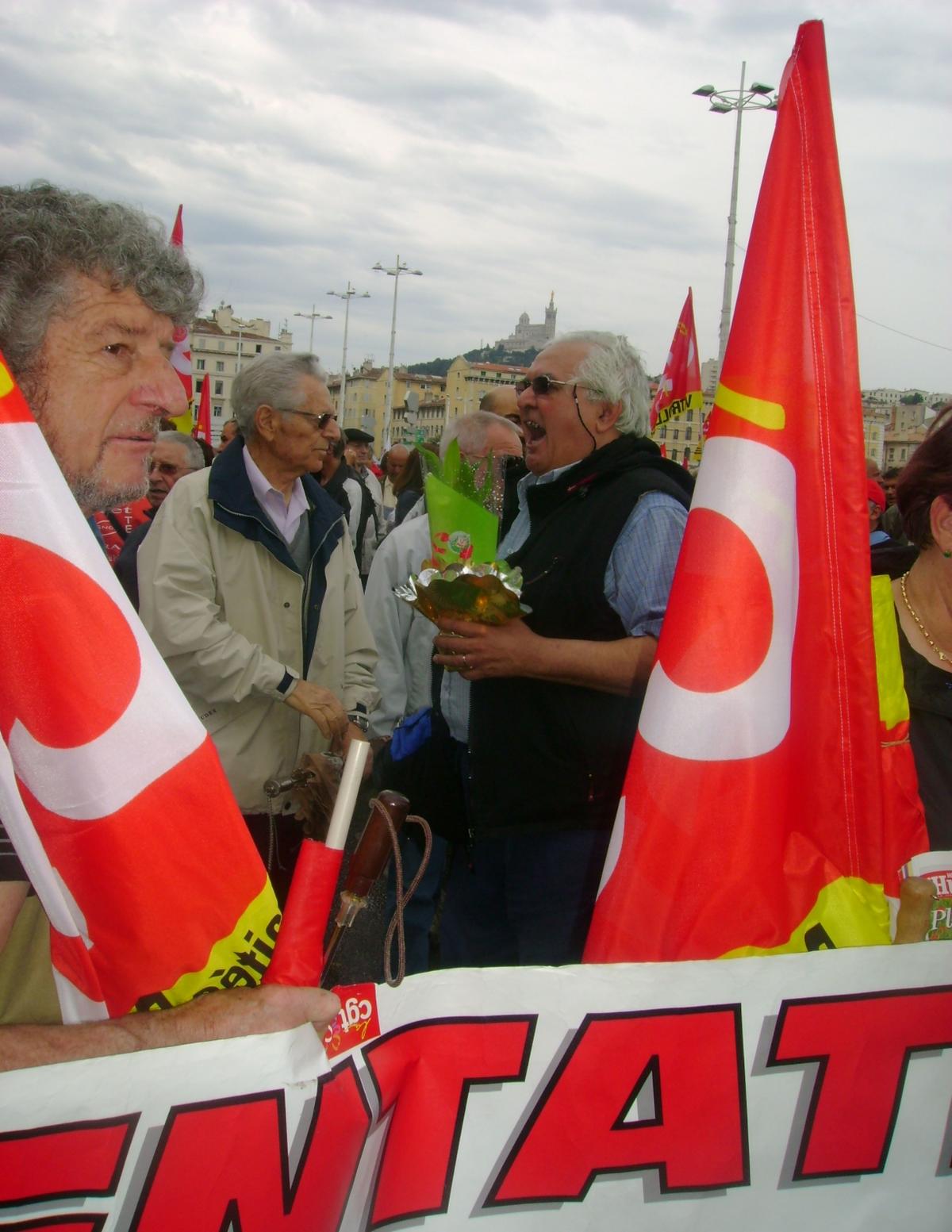 drapeau CGT et bouquet de muguet dans la mains,sous l'oeil bien veillante de notre dame de la garde au vieux port de Marseille