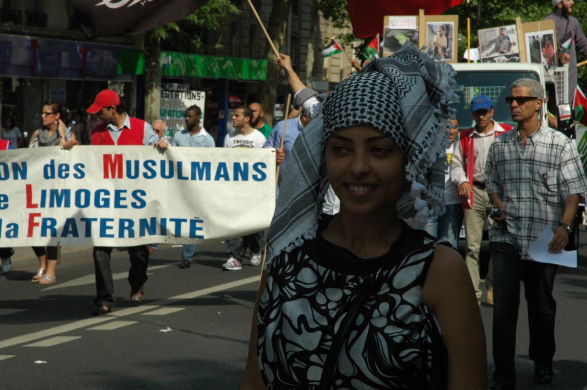 Jeune femme devant banderole Association des Musulmans de Limoges pour la fraternité.