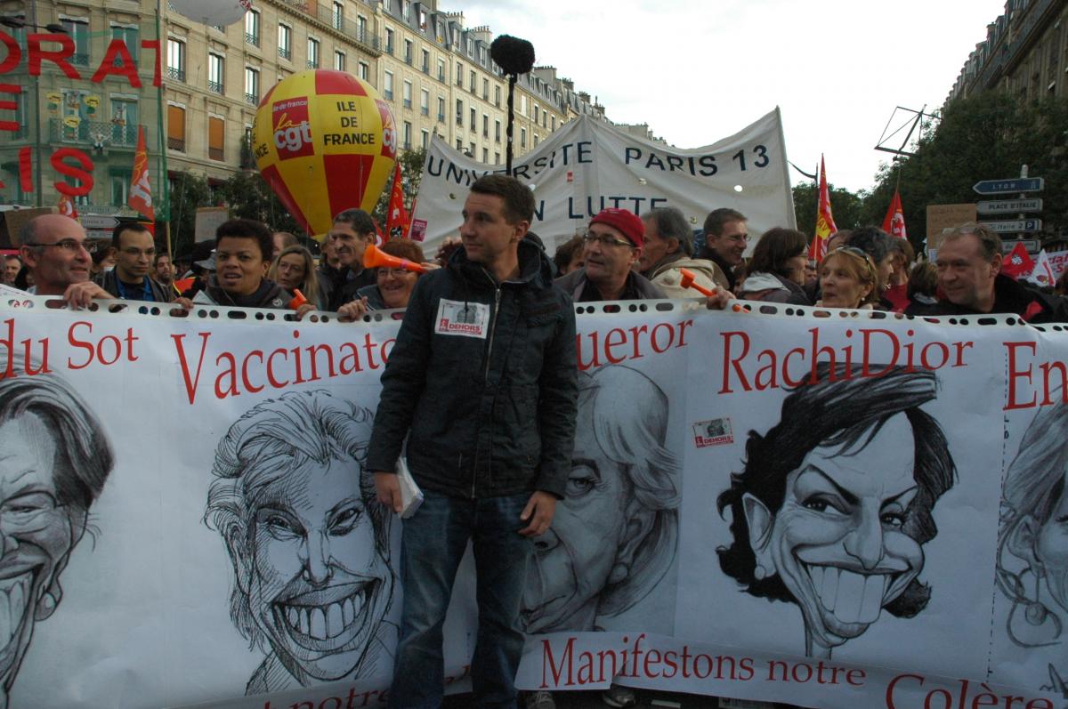 Olivier Besancenot devant banderole caricaturale d'élus gouvernementaux Paris.