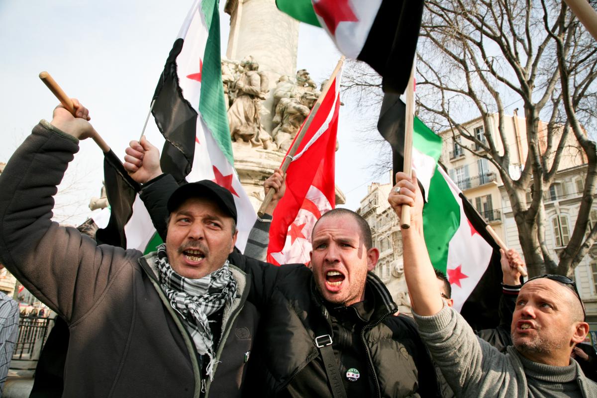 Manifestant brandissant les drapeaus syriens et tunisiens.