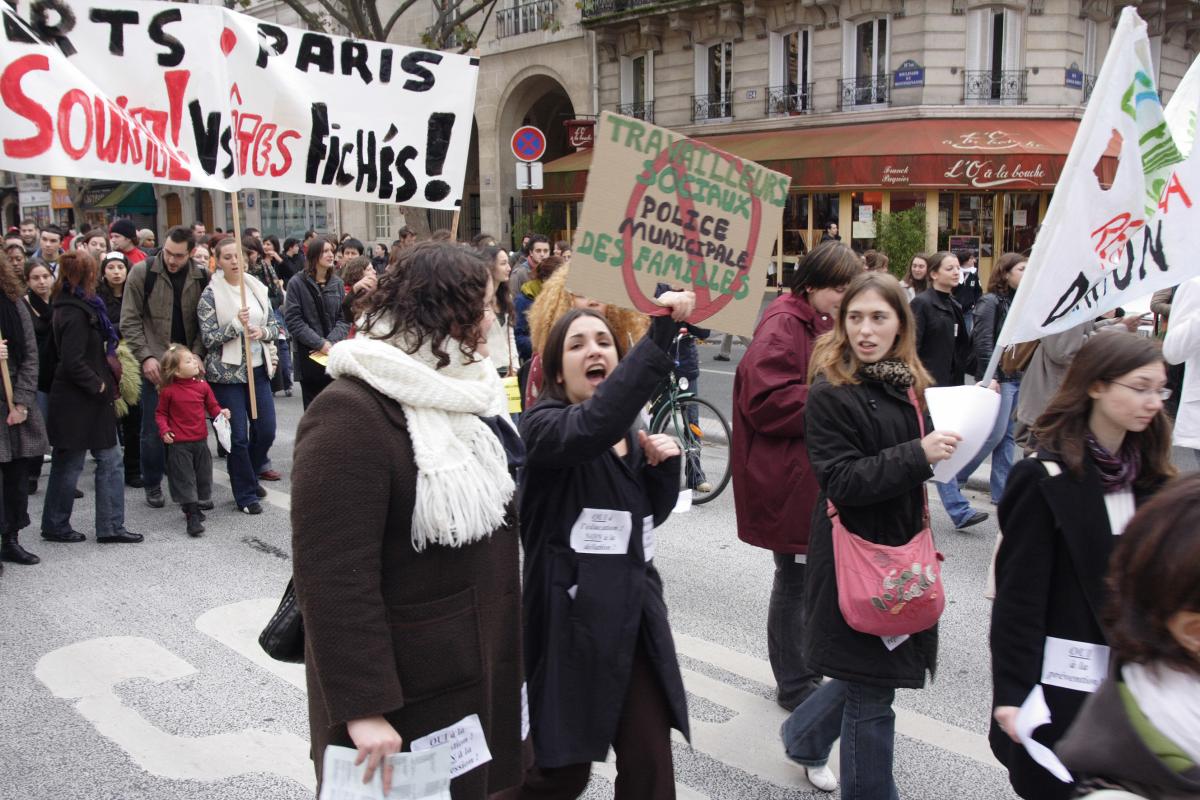 Manifestante avec pancarte : les travailleurs sociaux ne seront pas la police municipalee des familles
