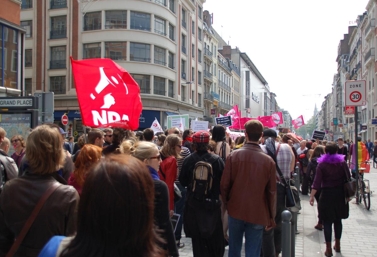 foule défilant lors de la marche des fiertés.On y distingue les banderoles et drapeaux du NPA, SOS HOMOPHOBIE, du Planning Familial
