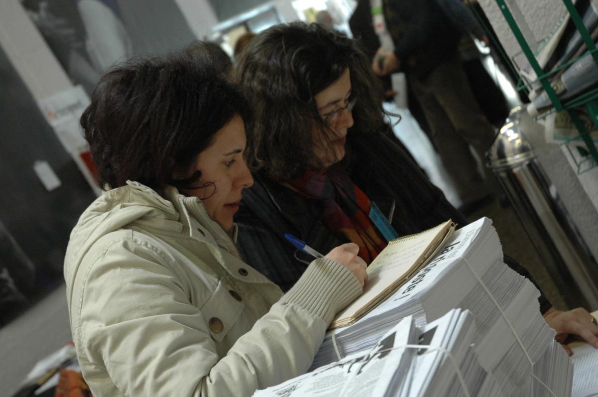 Deux militantes prenant des notes sur une pile de tracts