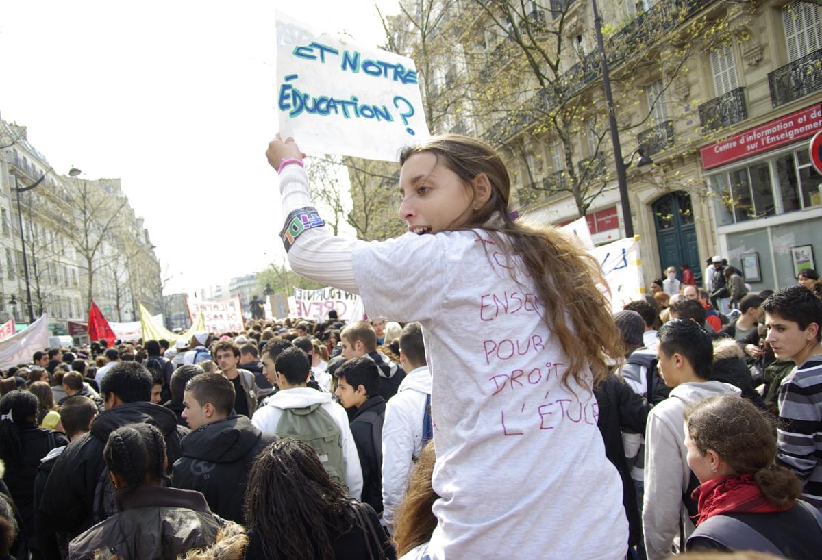 Lycéenne en blouse blanche avec une pancarte : et notre éducation ?