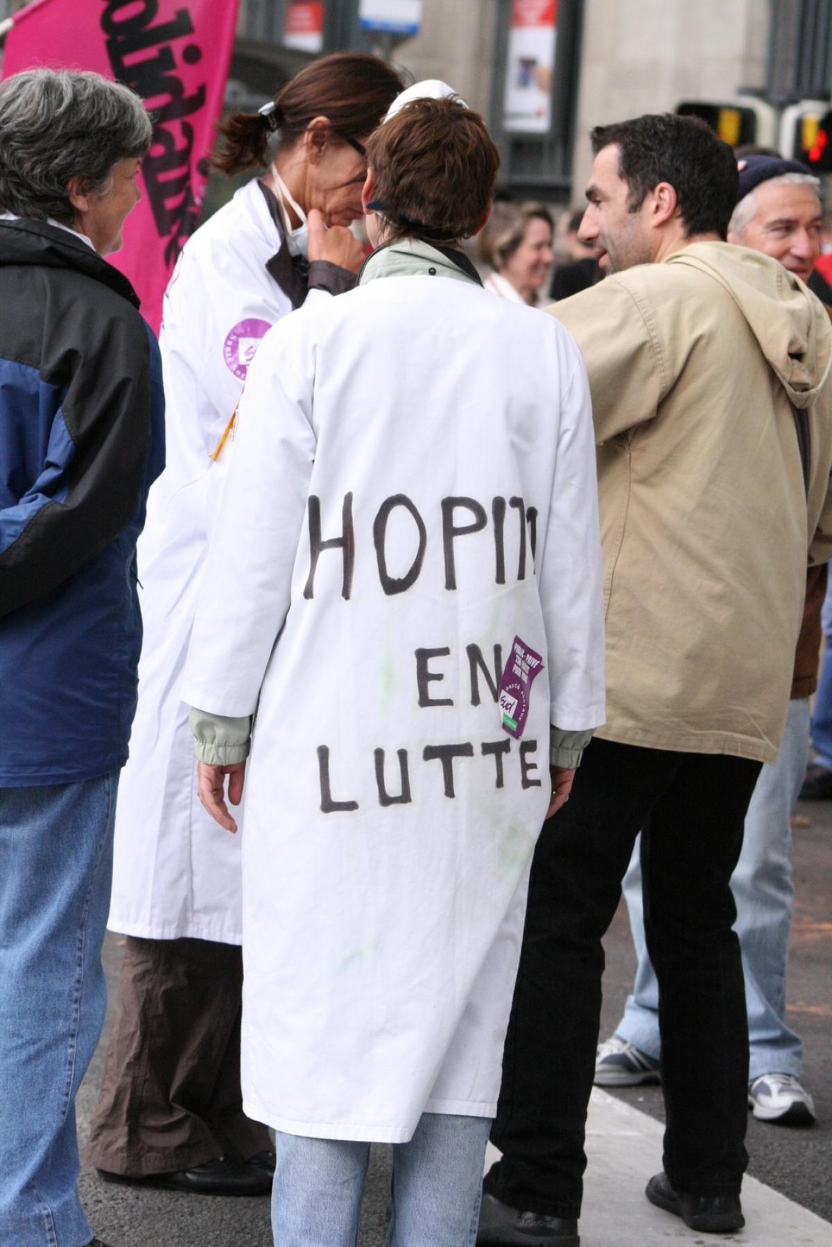 Infirmière avec hôpital en lutte écrit sur sa blouse blanche.