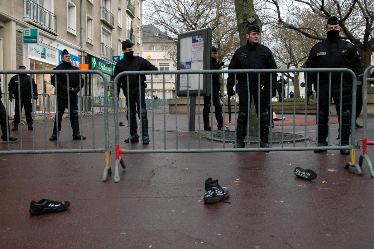 Policiers derrière une barrière avec chaussures au sol