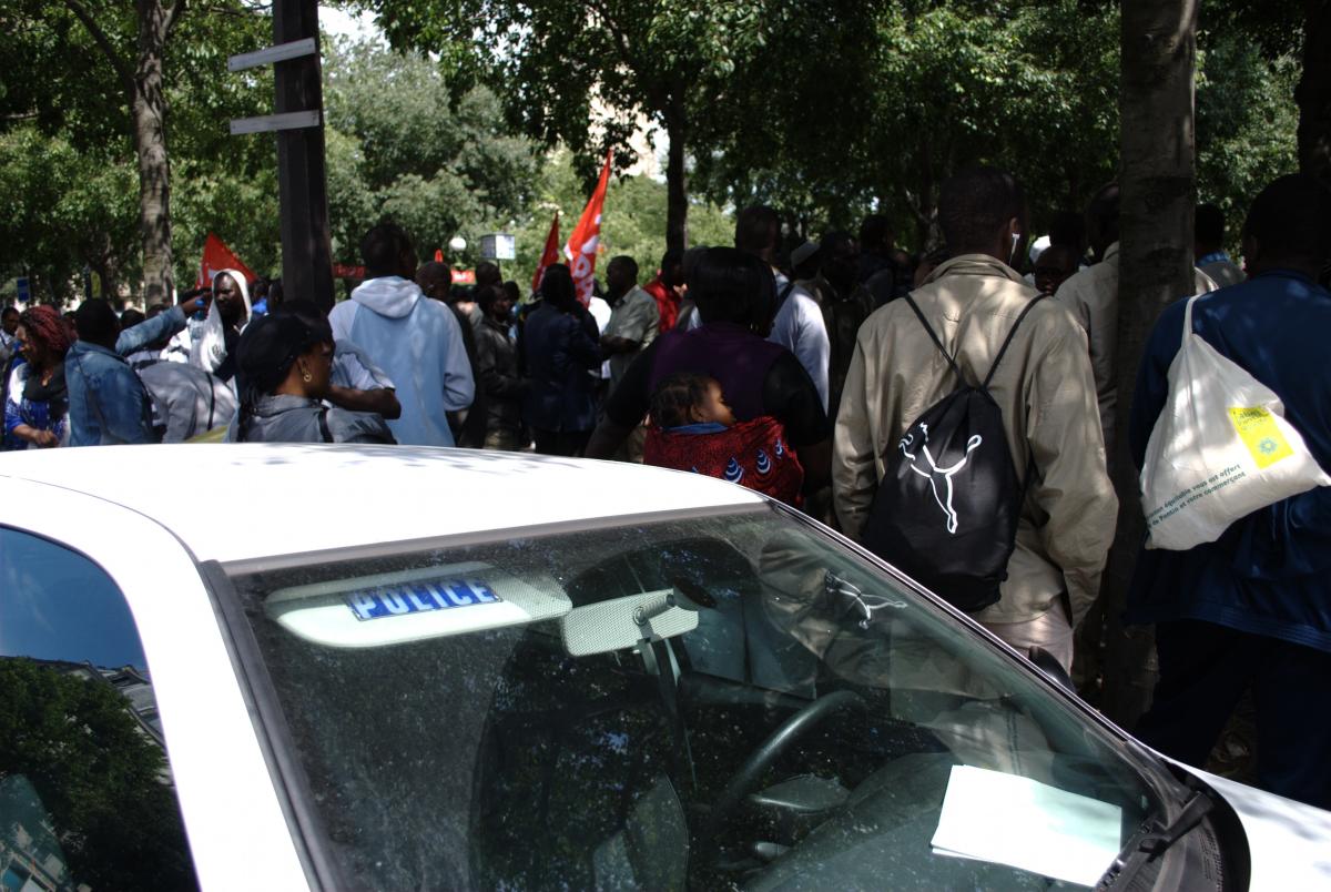 Une voiture de police, des manifestants sans-papiers