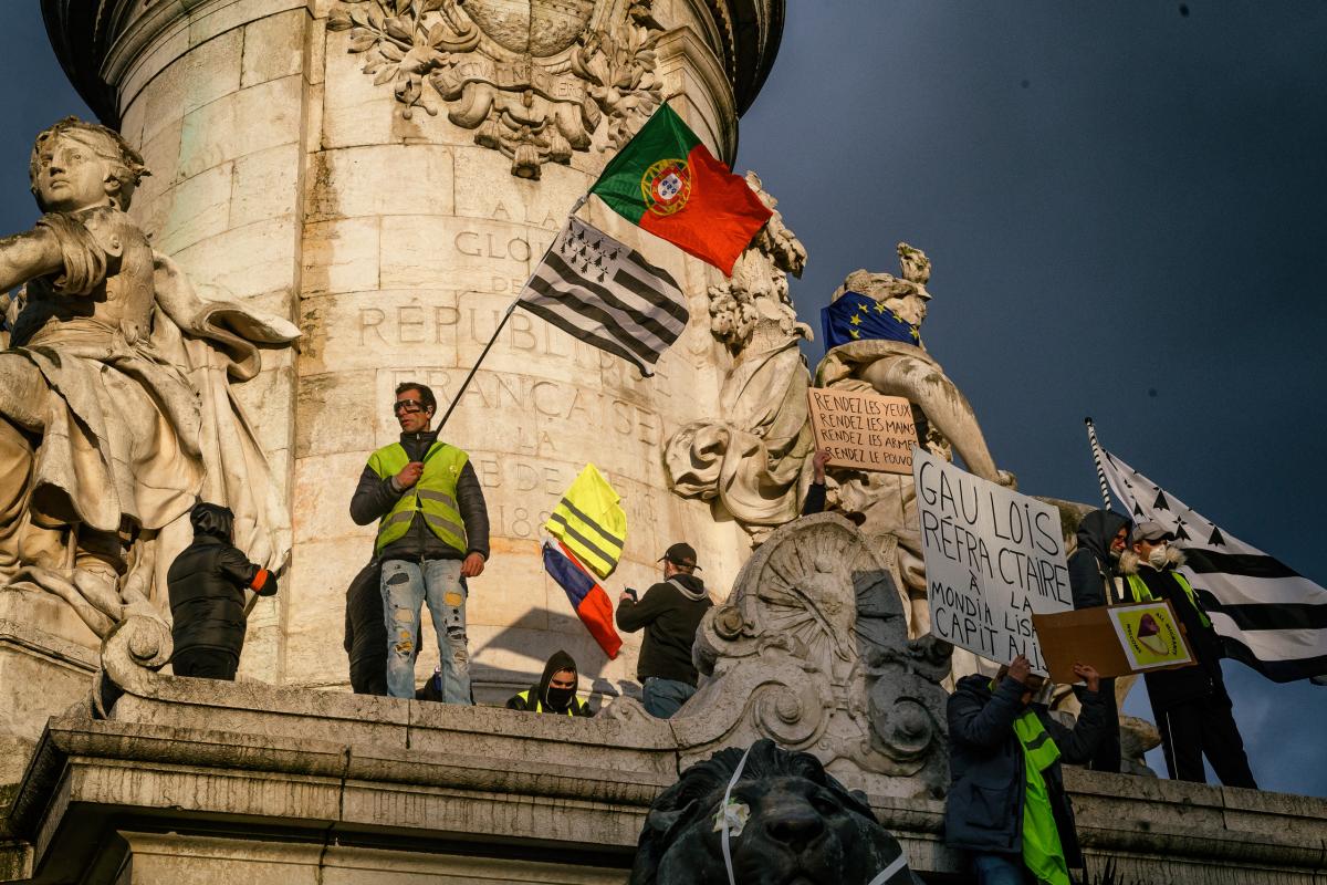Des manifestants avec des drapeaux sur l'estatue à la place de la république